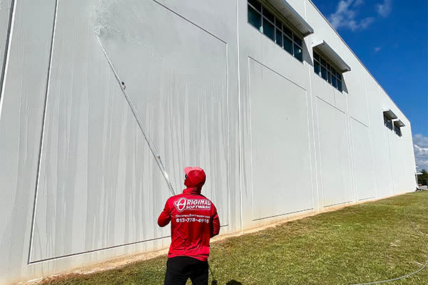 Tech soft washing a tall commercial building wall
